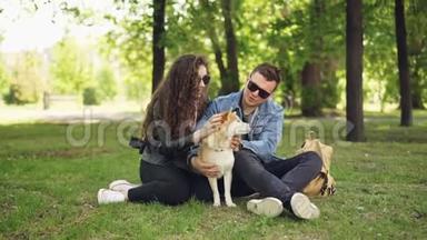 可爱的女孩和她的男朋<strong>友爱</strong>狗的主人周末在公园里拍宠物，聊天休息